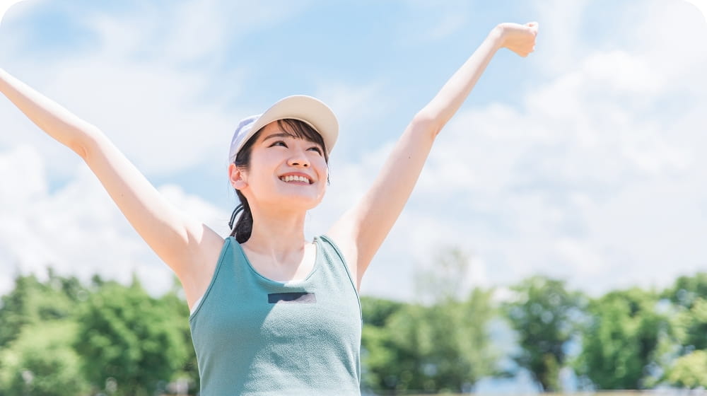 外で女性が両腕を挙げている様子